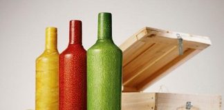 botellas roja verde y amarilla en una mesa con una caja detras y frutas