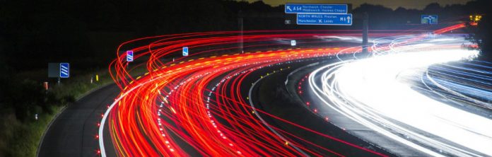 fotografia de una carretera de noche y coches pasando