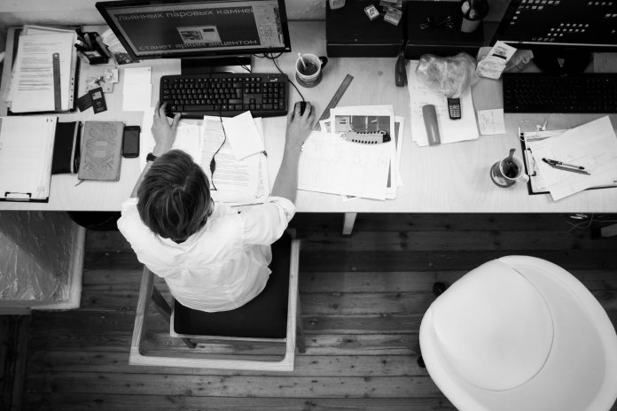 hombre con camisa sentado en una oficina visto desde arriba trabajando con el ordenador
