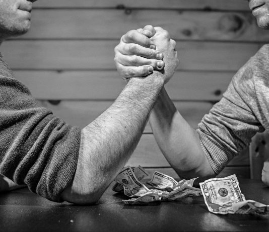 dos hombres haciendo un pulso sobre una mesa de un bar con billetes de dolar
