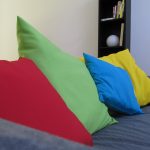 cojines de colores rojo verde azul y amarillo en un sofá oscuro