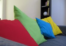 cojines de colores rojo verde azul y amarillo en un sofá oscuro