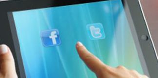 Manos sujetando una tablet con los logos de facebook y twitter