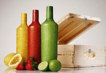 botellas roja verde y amarilla en una mesa con una caja detras y frutas