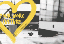 corazon amarillo dibujado con texto dentro "your work culture" sobre imagen de escritorio en oficina