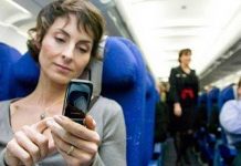 mujer con el pelo corto en el asiento azul de un avion usando el movil