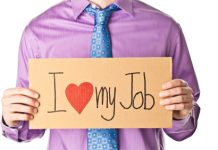 hombre con camisa morada y corbata sujetando un papel con mensaje de "i love my job"