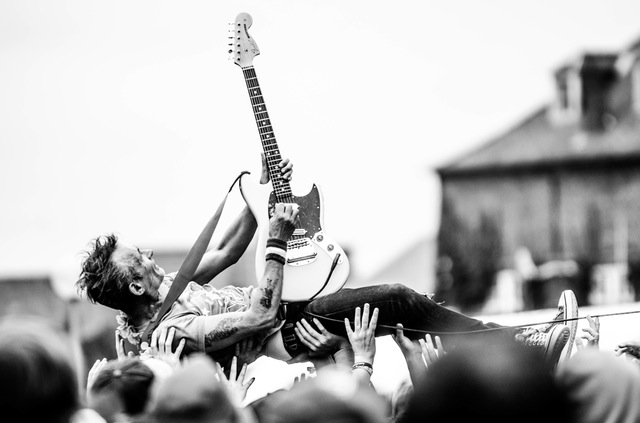 hombre rockero en un concierto tocando la guitarra electrica encima del publico