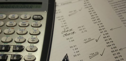 calculadora cientifica y boligrafo negro sobre una hoja con cifras llevando las cuentas