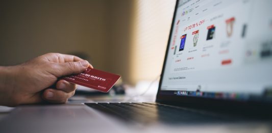 mano de una persona sujetando una tarjeta de credito para pagar una compra online